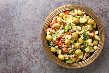 Healthy vegetarian vegetable salad with green olives, walnuts, tomatoes, cucumbers, parsley close-up in a plate on the table. Horizontal top view from above