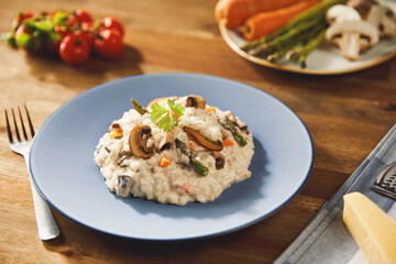 Risotto with mushrooms and asparagus on an old wooden table in blue plate