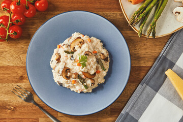 Risotto with mushrooms and asparagus on an old wooden table in blue plate