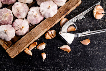Fototapeta na wymiar Garlic on a wooden tray with a garlic press.