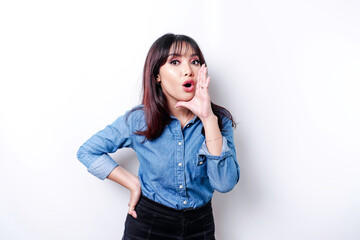 Young beautiful woman wearing a blue shirt shouting and screaming loud with a hand on her mouth. communication concept.