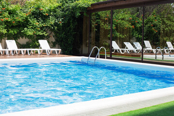 Modern blue water swimming pool with stair and wooden deck at hotel or a luxury house.