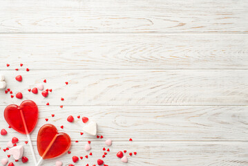 Valentine's Day celebration concept. Top view photo of heart shaped lollipops and candies on white wooden desk background with copyspace