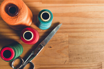 top view of stainless steel scissors and rolls of colored thread on a table with copy space. - Powered by Adobe