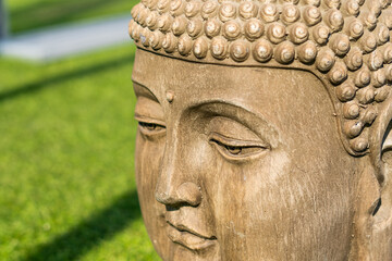 Buddha head statue, green natural blurred background. High quality photo