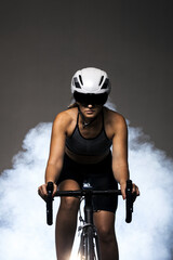 Obraz na płótnie Canvas Girl posing on roadbike. White protective helmet and black goggles. Cyclist against foggy background.