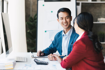 Young business people working and communicating while sitting at the office desk together.