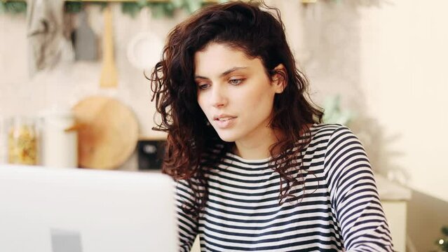 Portrait of attractive young woman student freelancer using laptop computer at home Charming dark haired female doing online job working studying or browsing web indoors
