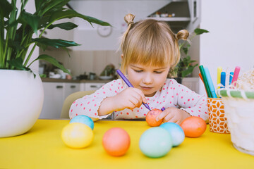 Smiling little girl with colorful eggs preparing for Easter Holiday. Kids painting easter eggs. Creative background for preschool and kindergarten. Family traditions and symbols of celebration.