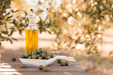 green olives and oil on table in olive grove