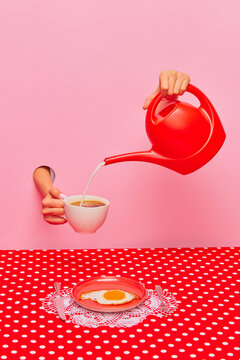 Food pop art photography. Female hand sticking out pink paper, pouring milk into coffee cup over plate with fried egg. Concept of taste, creativity, art. Complementary colors. Copy space for ad, text