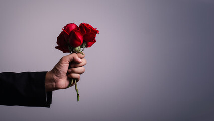 man hand wearing suite with red rose flower on background. holidays card with copy space valentine day celebration concept.