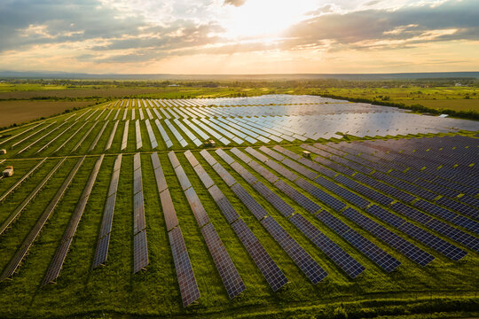 Aerial view of large electrical power plant with many rows of solar photovoltaic panels for producing clean ecological electric energy at sunset. Renewable electricity with zero emission concept
