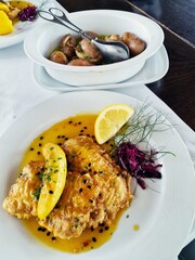 Filete de Espada with banana and passion fruit sauce. The black swordfish - the most typical fish on the island of Madeira. Typical madeiran dish Espada on white plate with potatoes as a side dish. 