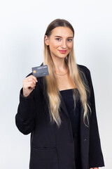 Happy caucasian female holding plastic bank credit card on hand. Professional company business woman over white wall background