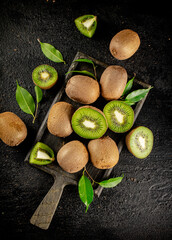 Pieces of kiwi with leaves on a cutting board. 