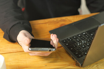 a person is watching a smartphone next to a laptop