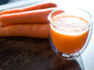Organic carrot juice in glass on dark wooden background