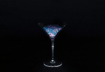 Martini glass with blue and pink jewelry stones in a black setting. Party concept, cocktail drink and crystal.