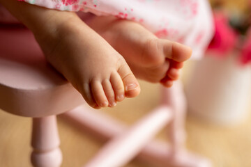Obraz na płótnie Canvas Baby's feet on a pink rocking chair