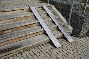 ramp combined with a gray concrete staircase and a handrail specially adapted for wheelchairs....