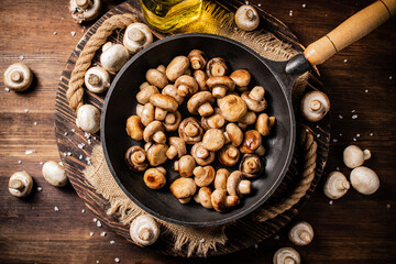 Fototapeta na wymiar Frying pan with fried mushrooms on a wooden tray. 