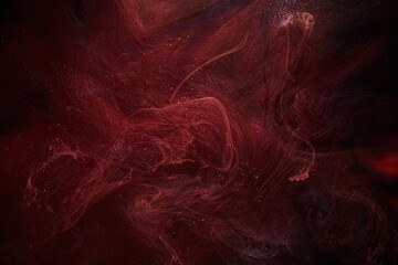 Red black abstract ocean background. Splashes and waves of paint under water, clouds of smoke in...