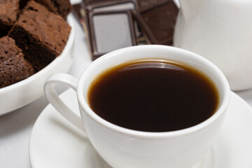 Coffee in a cup close-up, chocolate cake and pieces of chocolate on a white background