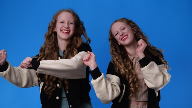 4k slow motion video of twin girls dancing over blue background.
