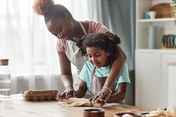 Candid loving mother and daughter baking together at home