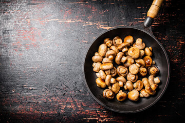 Fried small mushrooms in a frying pan. 