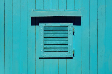 Obraz na płótnie Canvas Wooden window with closed shutters on blue shed