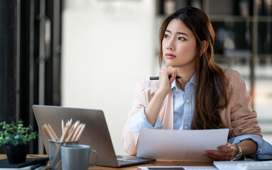 Serious young woman sitting at office, deep in thoughts, thinking concept