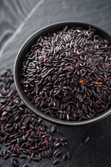 raw fresh black rice on black wooden rustic background
