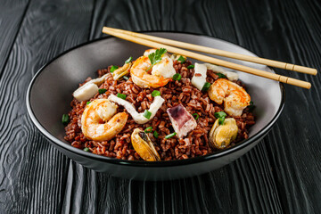 delicious red rice with shrimps and seafood on a black wooden rustic background