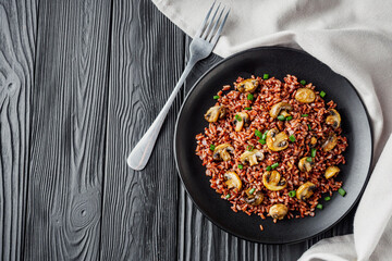 delicious red rice with mushrooms on a black wooden rustic background