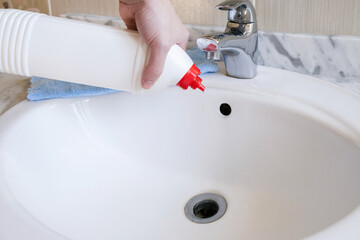 Removal of blockage in the sink, the hand of a man with a bottle of a special remedy with granules....