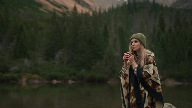 Tourist Woman With Hat Walking At Forest Lake In The Mountains And Drinking Hot Tea Or Coffee