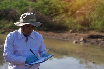 Asian man environment researcher holds tube of sample water to inspect from the lake. Concept, explore, analysis water quality from natural source. Ecology field research.    