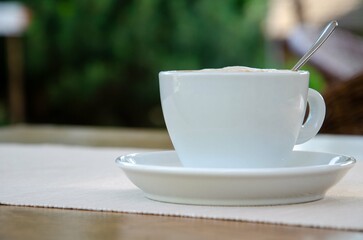 Cappuccino coffee in white cup on wood table.