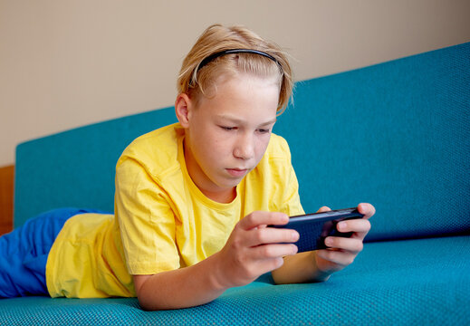 happy teennager looking at cell phone in living room at home