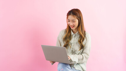 Naklejka premium Young women working and typing to chatting with colleague on laptop isolated on pink background