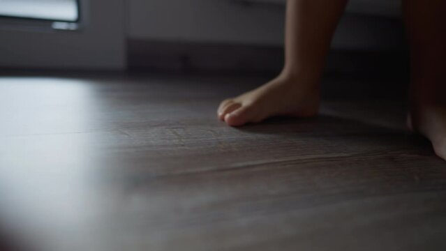 Child feet closeup on tiptoes at home. Little kid walking barefoot indoors
