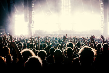 A crowd of people with raised arms during a music concert with an amazing light show. Black...