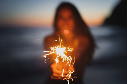 Woman with sparkler on seashore