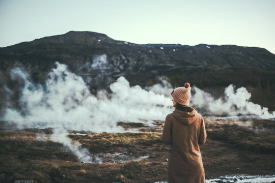 Back view of young tourist woman standing on the valley and enjoying the beautiful view of hot springs in Iceland.