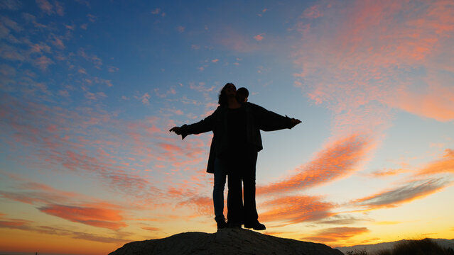 Silhouette of couple making airplane against beautiful sunset sky - Powered by Adobe