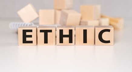 The word ETHICS is written on wooden cubes on a light grey background