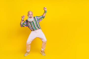 Fototapeta na wymiar Full length photo of positive good mood guy dressed striped shirt dancing looking empty space isolated yellow color background