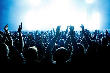 A crowd of people with raised arms during a music concert with an amazing light show. Black...